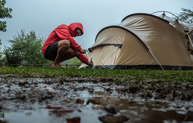 A person pitching a tent in the rain.